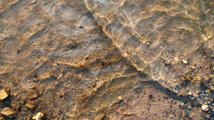 Top view on colorful pebbles covered by water. Close up view of smooth round pebble stones on the beach.