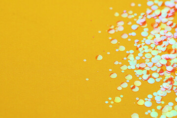 Fototapeta na wymiar Shiny bright glitter on yellow background, closeup. Space for text