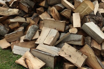 Pile of chopped firewood on grass outdoors