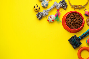 Flat lay composition with pet toys and feeding bowl on yellow background, space for text