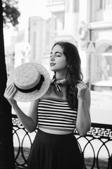 Fashion portrait of young, happy, elegant redhead curly woman, girl in hat and casual clothes. French style. Walking, relax in the city street. Sunny day.