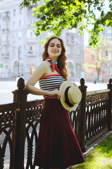 Fashion portrait of young, happy, elegant redhead curly woman, girl in hat and casual clothes. French style. Walking, relax in the city street. Sunny day.