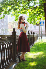 Fashion portrait of young, happy, elegant redhead curly woman, girl in hat and casual clothes. French style. Walking, relax in the city street. Sunny day.