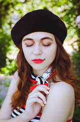 Fashion portrait of young, happy, elegant redhead curly woman, girl in hat and casual clothes. French style. Walking, relax in the city street. Sunny day.
