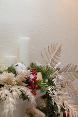 Christmas floral composition from fir branches, red berries and white cotton flowers. White Candles inside. Copy space, vertical shot