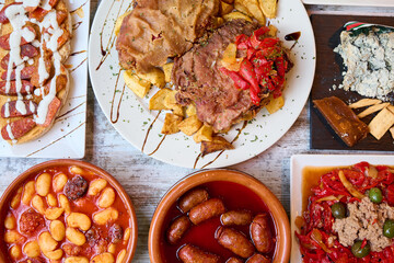 table with typical Asturian food, Asturian cachopo, Asturian bean stew, Cabrales cheese and sausage...