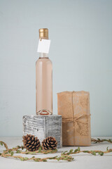 Fototapeta na wymiar 250 ml bottle of white or pink wine with blank label. Wrapped Christmas present, pine cones. Alcohol drink. Copy space