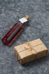 Bottle of red wine for Christmas celebration, mock up, no brand. Wrapped present box on grey wooden...
