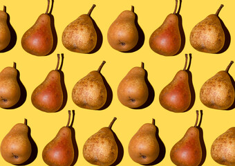 Colorful pear pattern. Orange Bera pears on a yellow background. Ripe juicy fruits with shadow top view. Food background. Creative concept.