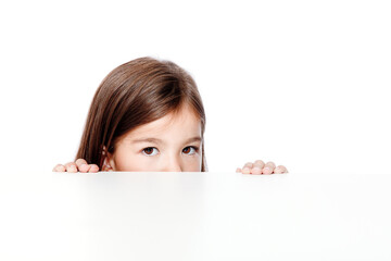 Cute little child girl looking up on the desk at school.