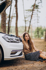 Fototapeta na wymiar Woman sitting by broken car in forest