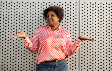 Curly african woman standing and showing whatever gesture