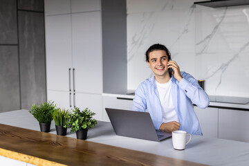Gig economy concept. Young positive man freelancer working remotely at home, looking at laptop and...