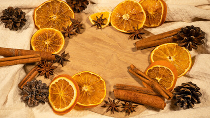 christmas winter food advent background - christmas scent, frame made of dried orange slices, cinnamon sticks and cloves, on rustic wooden table, top view