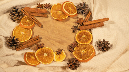 christmas winter food advent background - christmas scent, frame made of dried orange slices, cinnamon sticks and cloves, on rustic wooden table, top view