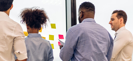 Casual creative happy smile business people plan strategy analysis and brainstorm putting post it sticker note to share idea for startup project on glass board at modern office