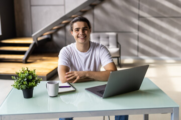 Successful man smiling in satisfaction as he checks information on his laptop computer while working