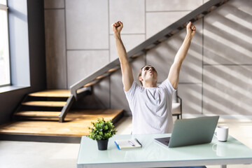 Happy man celebrate great news opportunity got read by e-mail. Excited man sit in kitchen look at laptop screen with clenched fists feels incredible amazed received good notice. Sale, discount concept