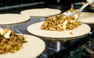 Preparation of a pastry with puff pastry and minced meat stuffing with chopped boiled egg, onion, garlic and green seasoning. Mention food preparation in the kitchen at home, fast and practical food.