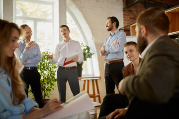 Group of young people, businessmen at business meeting at office space. Scientific conference event, training, brainstorm.