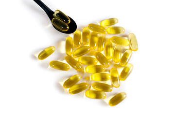 Fish oil capsules on a white background and a black spoon. A spoonful of fish oil capsules. Dietary...