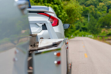 A tow truck with a broken car on a rural road