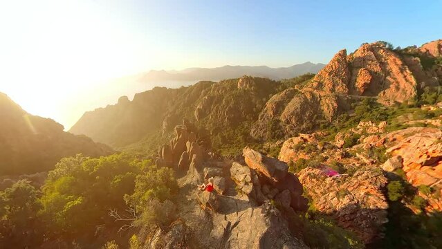 Aerial view of a tourist woman on top aerial view of sunset badlands Calanques of Piana. Drone view on the road in Corsican badlands called Les Calanques in Mediterranean sea by the Porto Ota