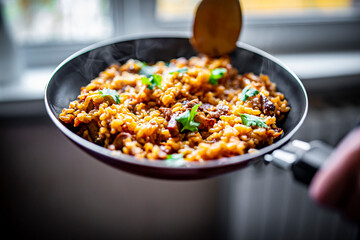 cooking tasty rice, meat and vegetable in pan on kitchen