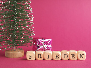 Small wooden blocks with the German inscription peace, Merry Christmas, purple background