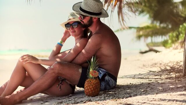 Beautiful Couple Sitting Together On Tropical Beach.Attractive Lovers Vacation Travel At Sea.Happy Romantic Couple Enjoying Relaxing Ocean On Caribbean Resort.Honeymoon Holidays On Maldives Or Bahamas