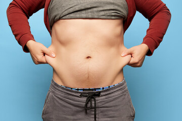 Naklejka premium Cropped image of man showing his belly, abdomen. Close Up part of man's body. Concept of dieting, sport, fitness, healthy lifestyle, body positive