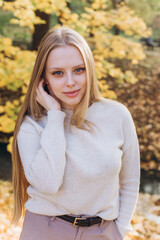 Close up blondie woman outdoor portrait in autumn park. Happy caucasian girl with long natural blondie hair 