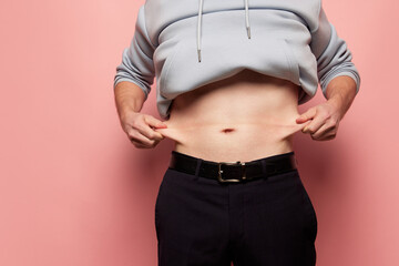 Cropped image of man showing his belly, abdomen. Close Up part of man's body. Concept of dieting, sport, fitness, healthy lifestyle, body positive