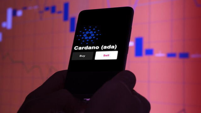 An investor's analyzing the cardano (ada) coin on screen. A phone shows the $ADA crypto's prices to invest