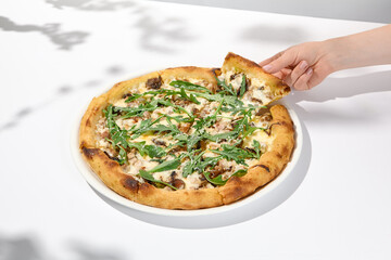 Woman eat italian pizza on light background. Female hand holding piece of pizza. Hand take cheese pizza Trendy italian menu. Person holding italian food