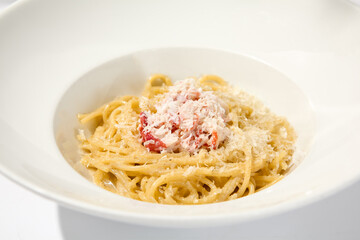 Spaghetti with crab meat and cheese on white table with shadows. Seafood pasta with spaghetti and crab in summer italian menu Italian pasta with parmigiano cheese and crab meat