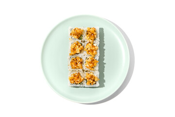 Sushi topped burnt shrimp tartare. Maki sushi with shrimp and spicy sauce on ceramic plate Baked maki roll topped shrimp tartare isolated on white background with hard shadow