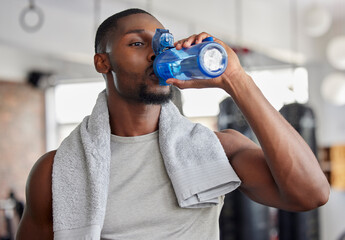 Water, drink and fitness with a sports man in a gym for exercise while taking a break to hydrate. Workout, training and drinking with a male athlete taking a sip from a bottle after his routine - Powered by Adobe