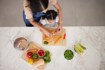 Cooking, vegetables and mom with child in kitchen cutting, peeling and prepare food. Child...