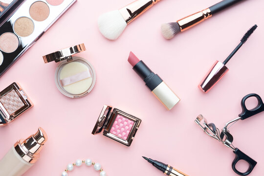 Top view of beauty cosmetic makeup accessories on pink background. Fashion woman make up product, brushes, lipstick, powder, foundation collection.