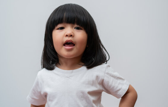 Portrait Of Happy And Funny Asian Child Girl On White Background, A Child Looking At Camera Hand Gesture. Preschool Kid Dreaming Fill With Energy Feeling Healthy And Good Concept