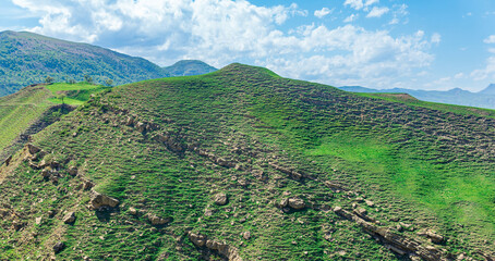 natural mountain landscape, mountainside with stones, grass and trails of goats