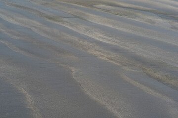 black volcanic sand beach with wave patterns