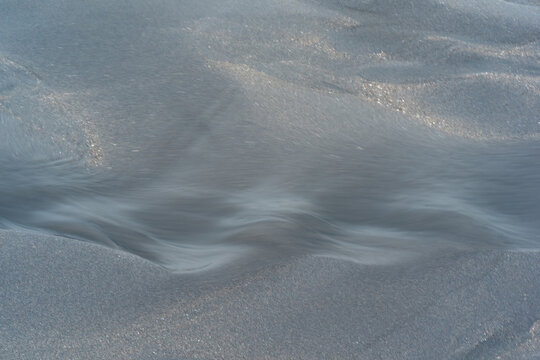 blurred natural background, water flows along the beach from black volcanic sand