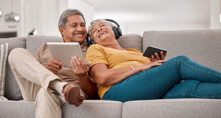 Phone, tablet and headphone with senior couple relax, listening to music and social media on lounge sofa in home. Happy elderly man and woman streaming 5g online during retirement at house in brazil