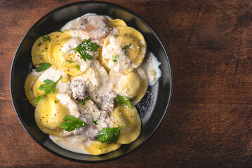Ravioli with mushroom creamy sauce and mushroom stuffing with herbs and ground pepper. Winter recipes for the cold season of Italian cuisine, copy space