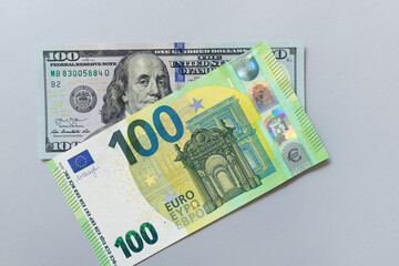 US dollar and euro banknotes. 100 $ one hundred dollars and €100 one hundred Euros papers exchange rate isolated on grey background