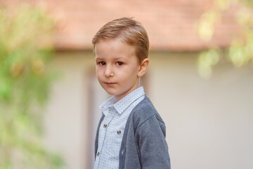 portrait of a blond boy outside in natural light, the boy staring straight into the camera