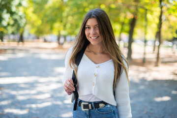 Smiling female college student walking outdoor in a park