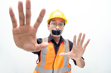 Young asian construction worker doing protest by covering mouth with tape isolated over white...
